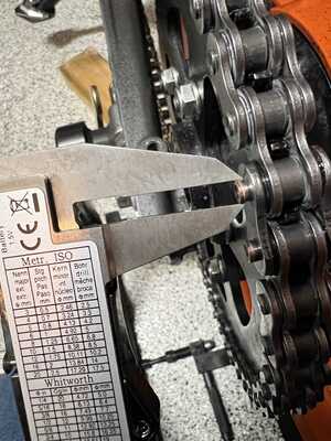 Shows a caliper being used to measure the riveting of the master link.